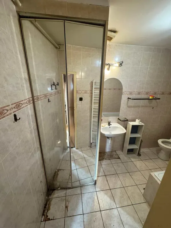 Pôvodná kúpeľňa pred rekonštrukciou — sprchový kút a umývadlo s pásom ozdobných dlaždíc — Ružinov - Bratislava
